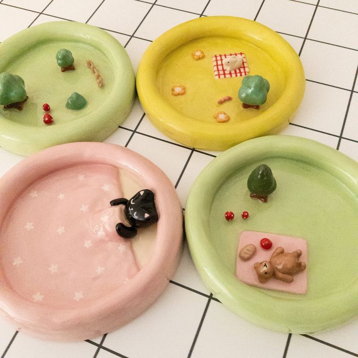 four plates with small toys on them sitting on a tiled floor next to each other