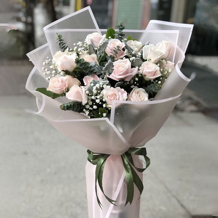 a bouquet of white roses tied to a pole on the sidewalk in front of a building