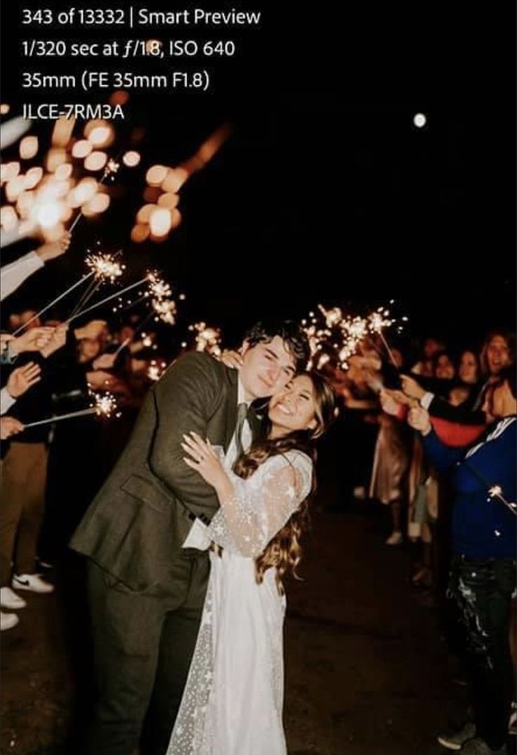 a bride and groom kissing while surrounded by sparklers