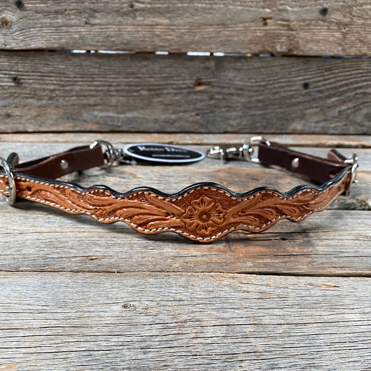 a brown leather belt with silver buckles on wooden planked floor next to wood wall