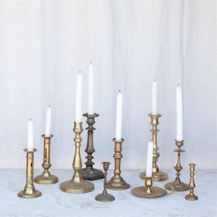 a group of brass candles sitting next to each other on a white tablecloth covered floor