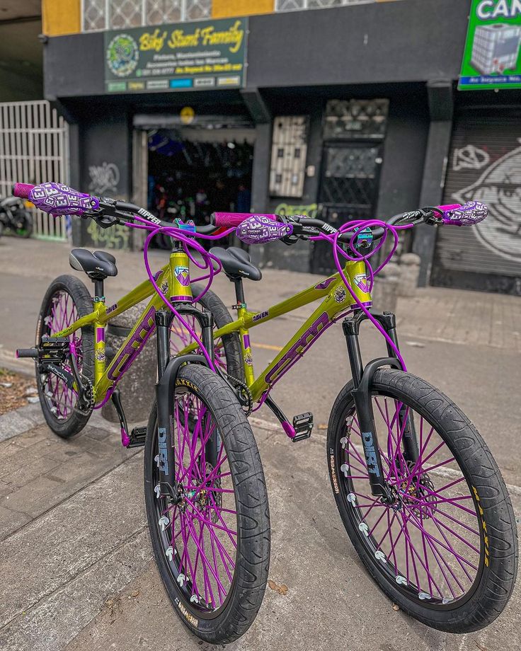 two purple and green bikes parked on the street