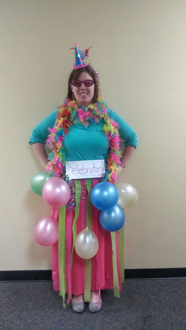 a woman in a hula skirt holding balloons and a sign