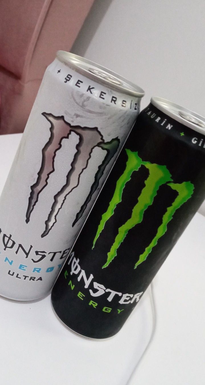 two cans of monster energy drink are sitting on a white countertop next to each other