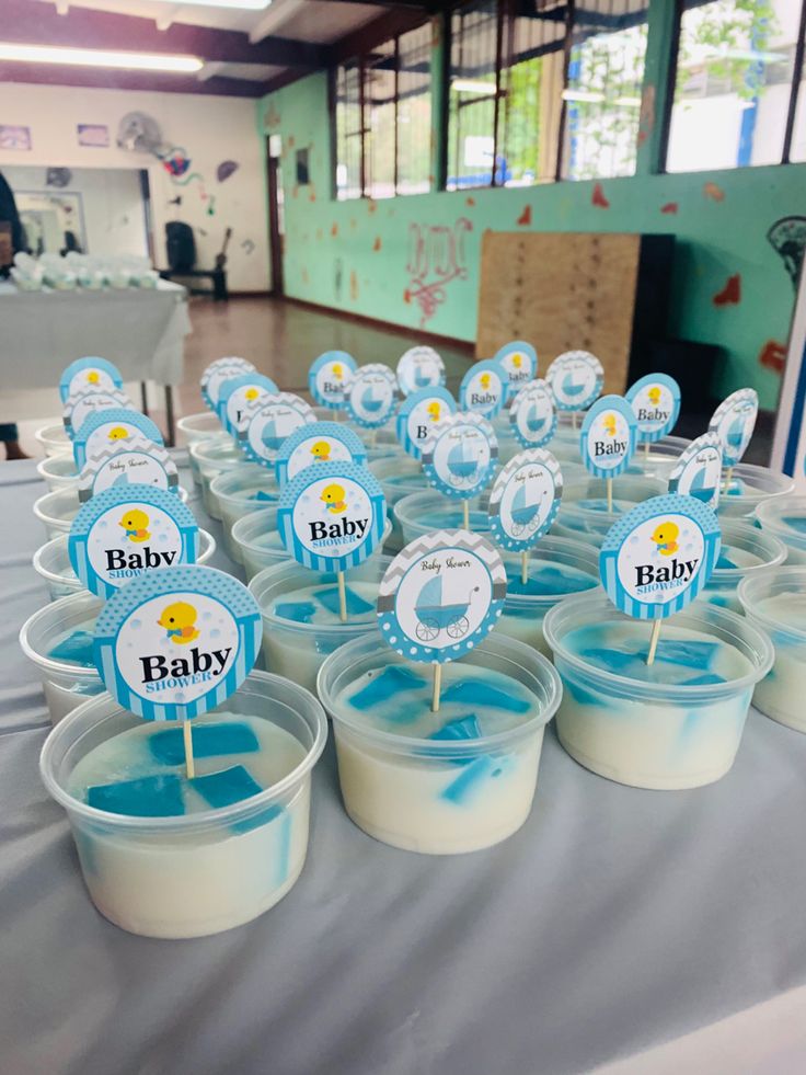 baby cupcakes are sitting in plastic cups on a table with blue and white decorations