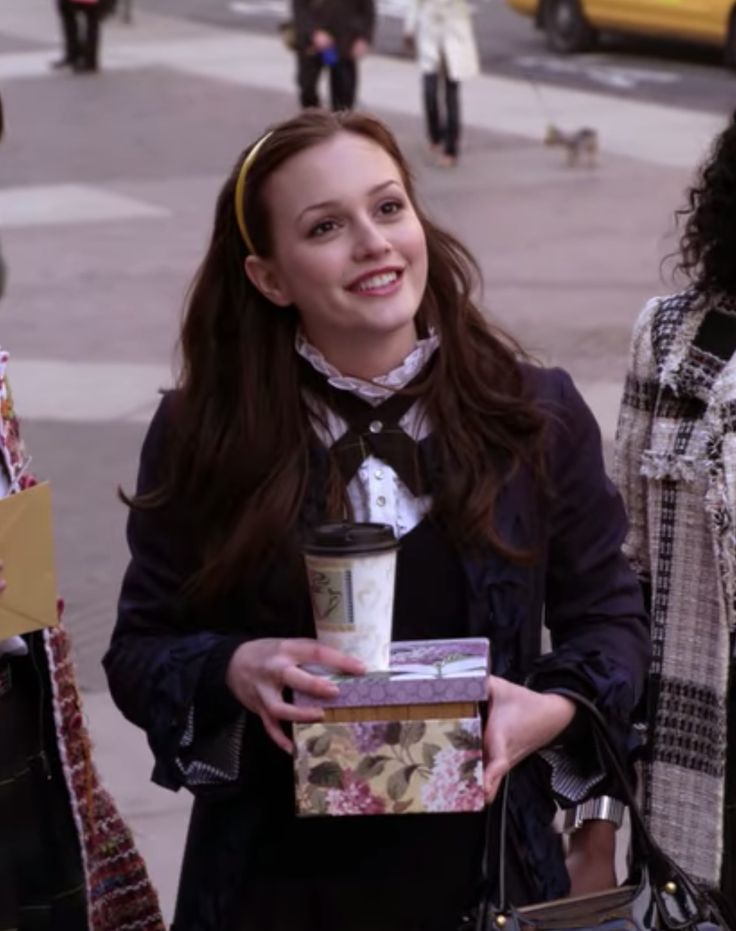 a woman holding a coffee cup in her hand while standing next to other women on the street