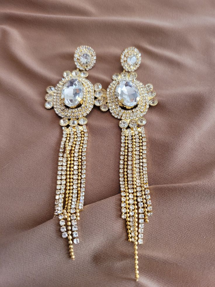 The earrings have a one carat round Austrian crystal with 1mm round accented posts.  The tassel drop is Victorian style with a 10 carat oval Austrian crystal with 1mm to 3mm round accents.  The tassel is made of 1mm round Austrian crystal accents and rope chain.  14K gold plated. Crystal Tassel Drop Earrings As Gift, Crystal Tassel Drop Earrings For Gifts, Elegant Rhinestone Tassel Drop Earrings, Elegant Drop Earrings For Celebration, Elegant Evening Jewelry With Tassels, Silver Elegant Tassel Drop Earrings, Elegant Silver Earrings With Tassels, Elegant Rhinestone Dangle Tassel Earrings, Elegant Silver Tassel Drop Earrings