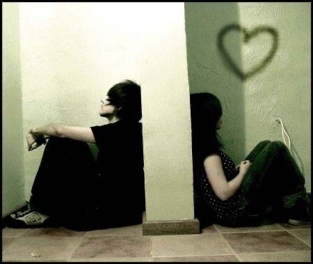 two people sitting on the floor in front of a wall with a heart drawn on it