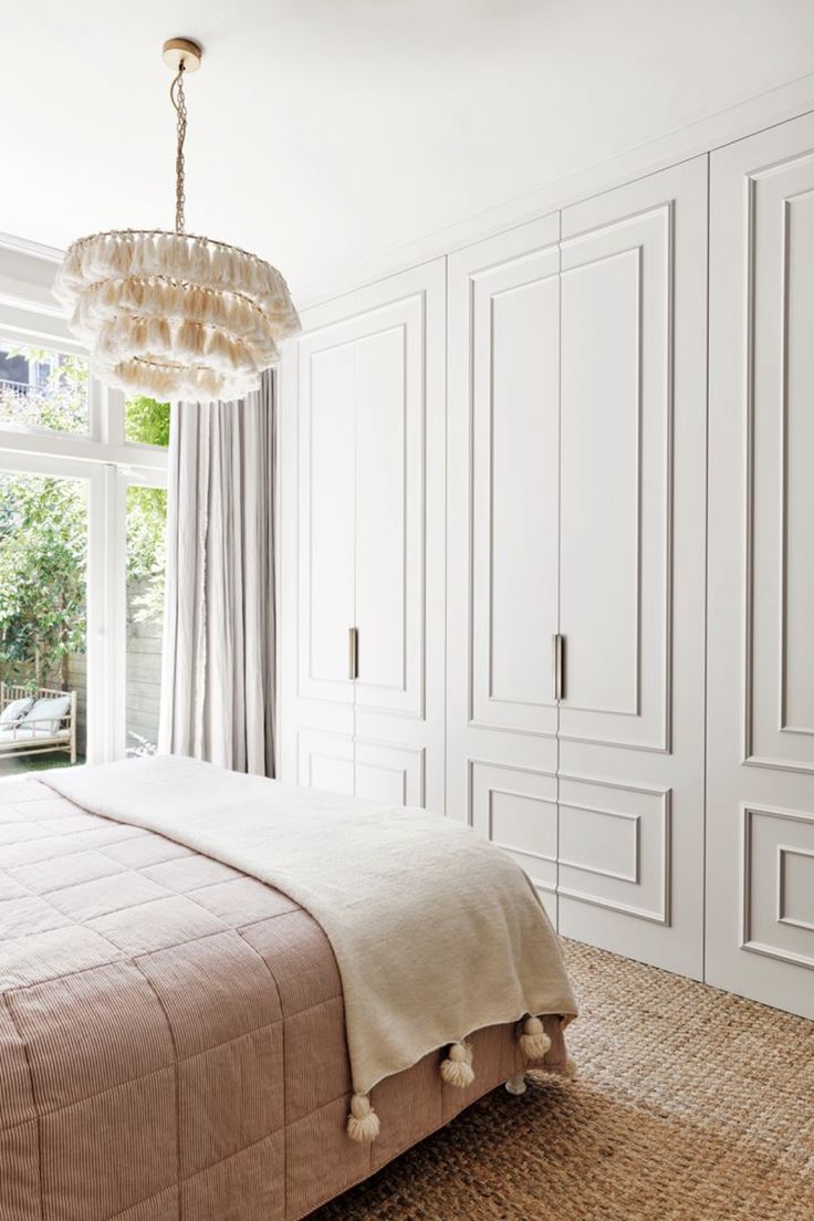 a bedroom with white closets and a chandelier hanging from it's ceiling