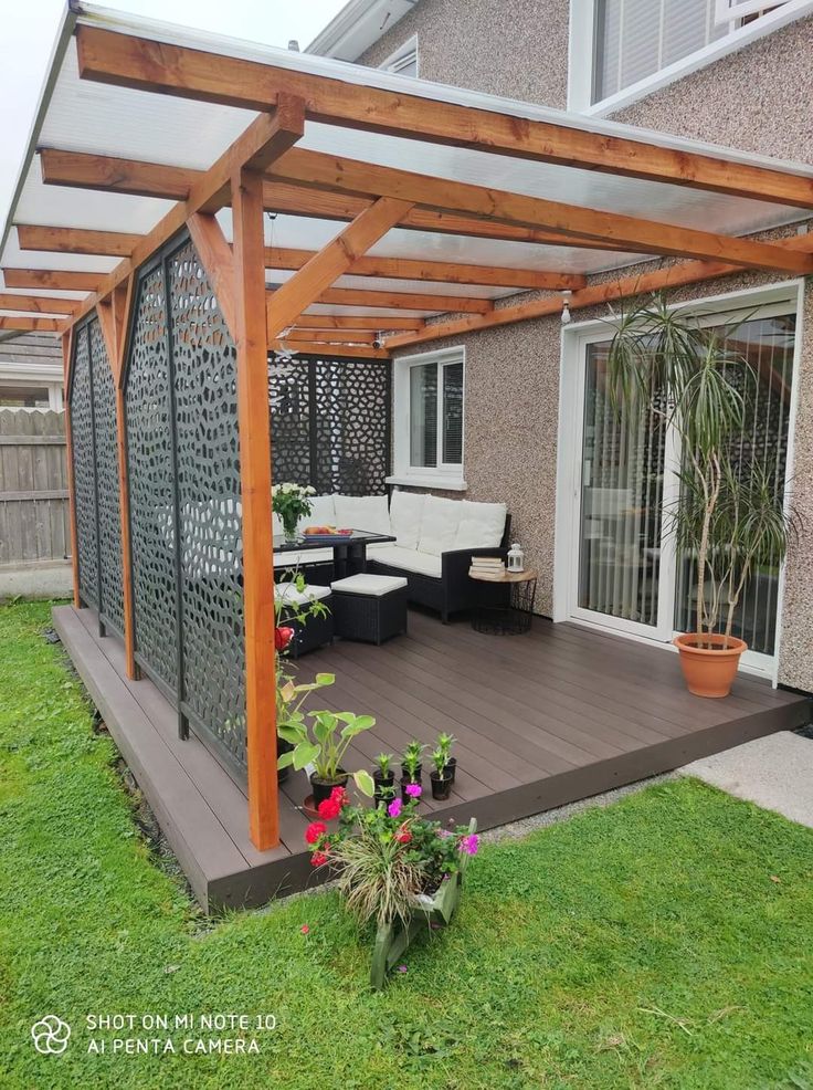 an outdoor patio with wooden pergols and plants on the grass in front of it