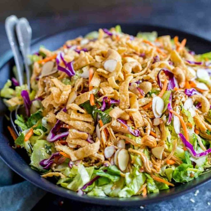 a salad with shredded carrots, lettuce and almonds in a bowl