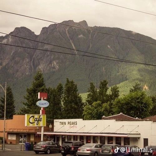 cars parked in front of a cafe with mountains in the background