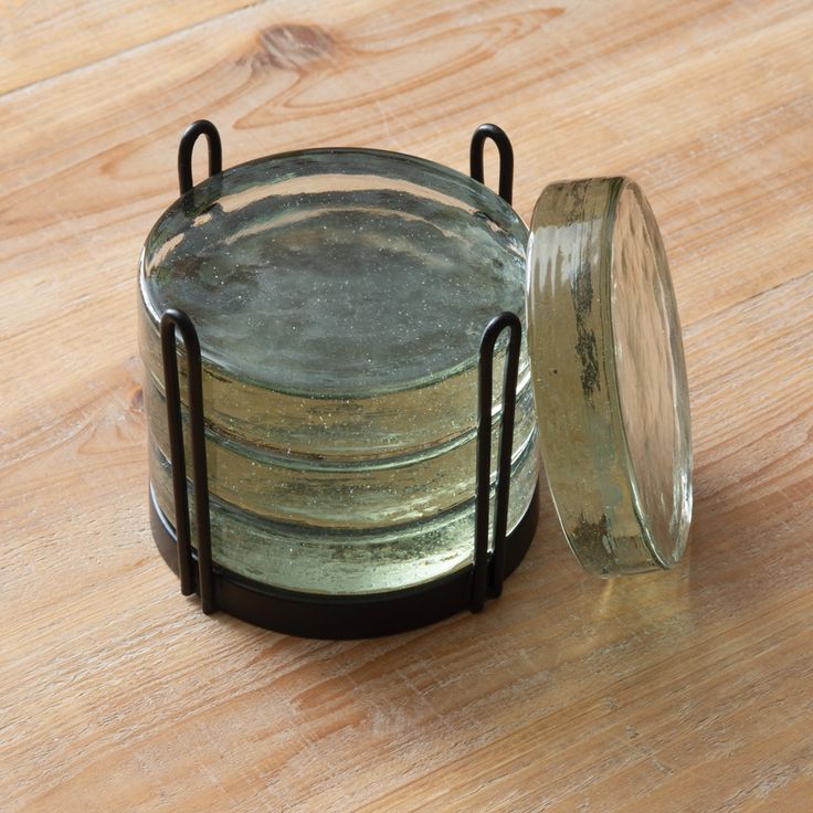 an empty glass jar sitting on top of a wooden table next to a metal holder