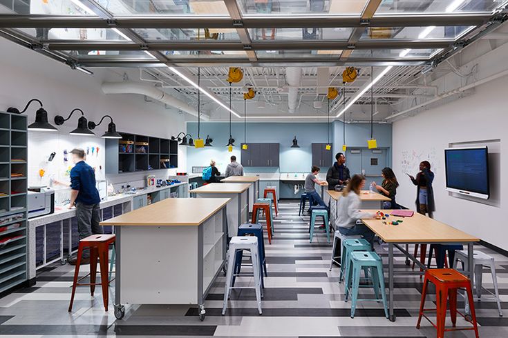 people are sitting at desks in an open kitchen area with checkered flooring