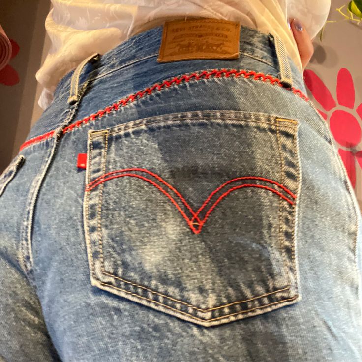 the back of a woman's jeans with red stitching on her butts