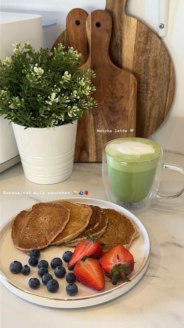 a white plate topped with french toast and berries next to a cup of green tea