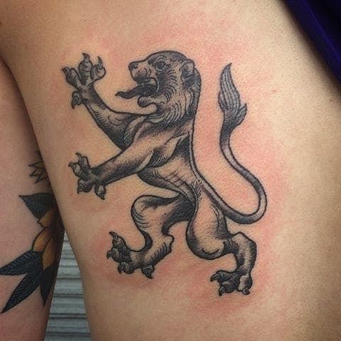 a lion tattoo on the back of a woman's thigh