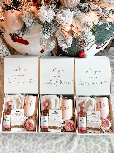 four bottles of perfume sitting in front of a christmas tree with greeting cards on it