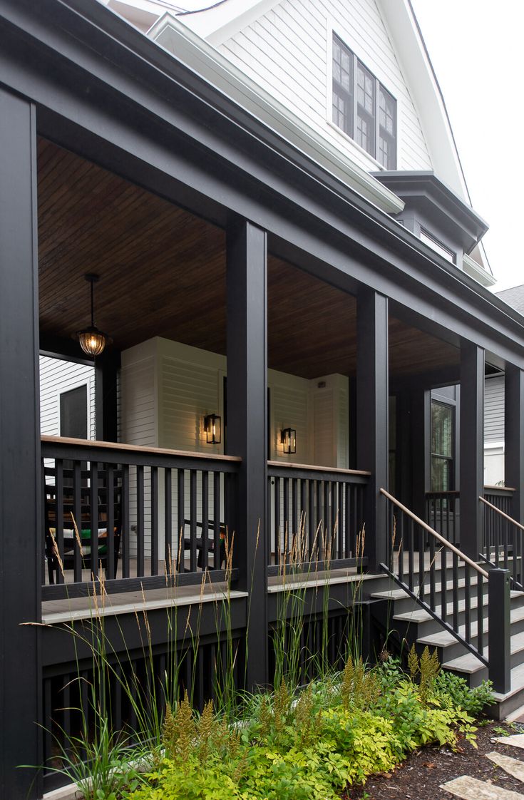 the front porch of a house with black railings and wood steps leading up to it