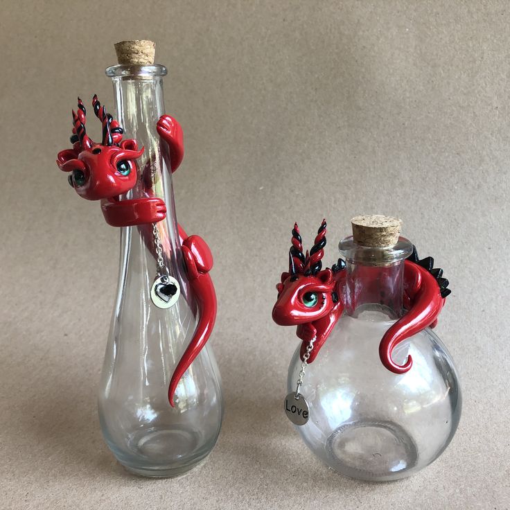 two glass vases with red and black designs on them, one has a dragon in it