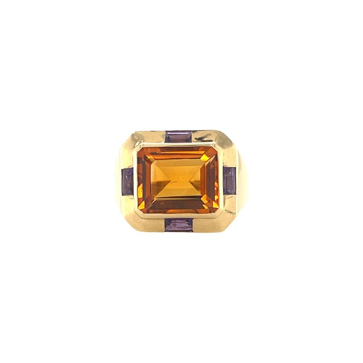 a yellow gold ring with an orange and purple stone in the center on a white background