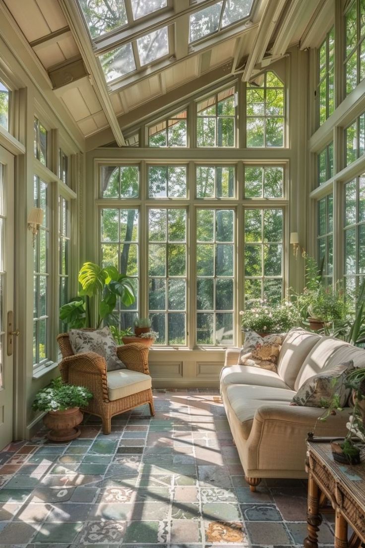 a sun room with lots of windows and plants on the floor in front of it