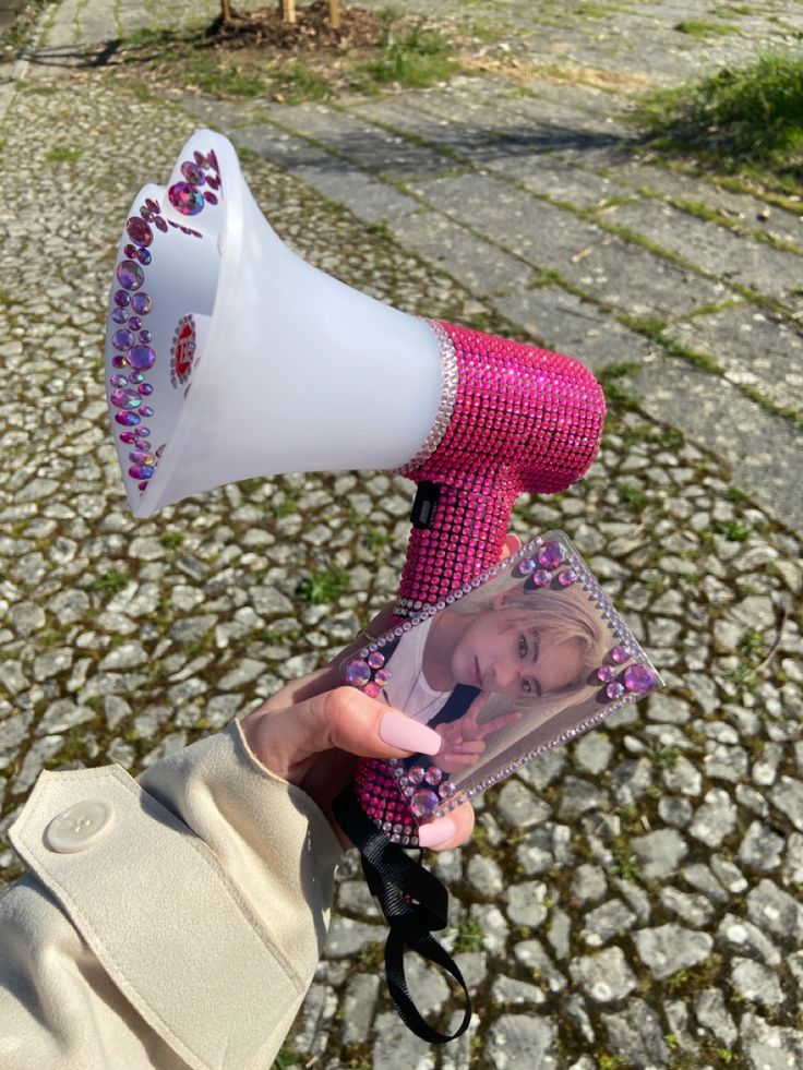 a person holding a pink and white hair dryer in their hand on the street