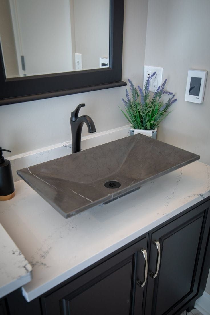 a bathroom sink sitting on top of a counter next to a vase with flowers in it