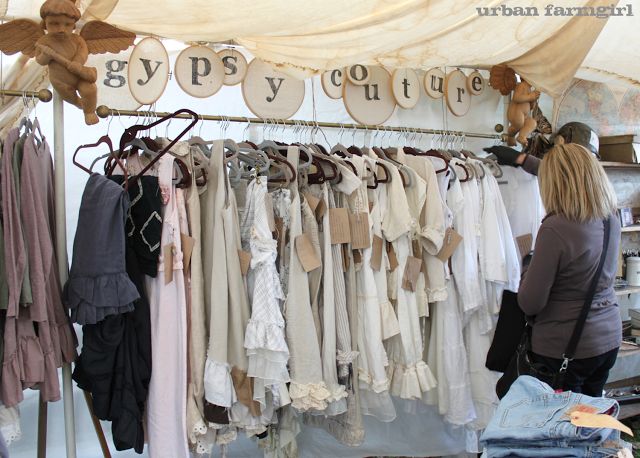 a woman standing in front of a display of clothes on hangers and hanging from the ceiling