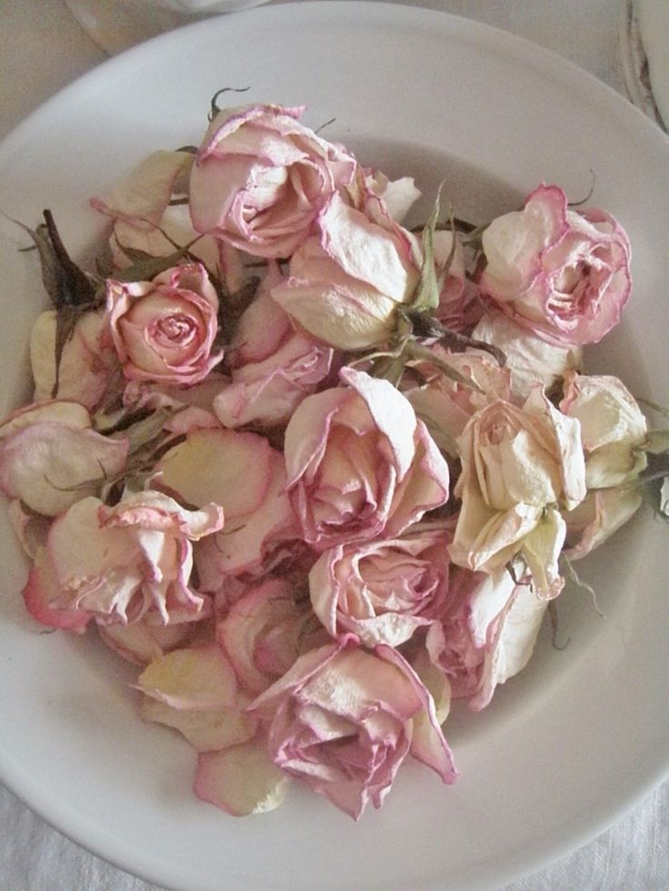 a white bowl filled with pink flowers on top of a table