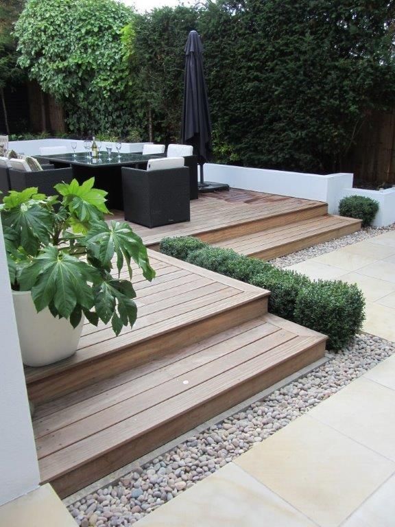 an image of a backyard with steps and plants on the decking area that is made out of wood planks