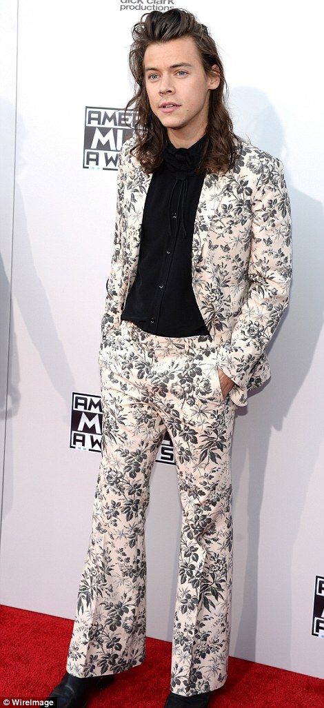 a man with long hair in a suit and tie on the red carpet at an event