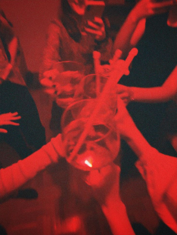 a group of people standing around each other with their hands in the air and holding wine glasses