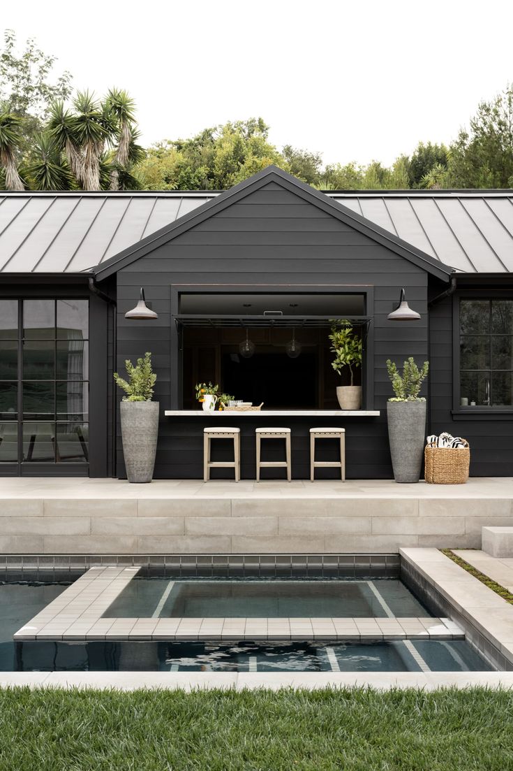 an outdoor kitchen and dining area is shown in the background, with potted plants next to it