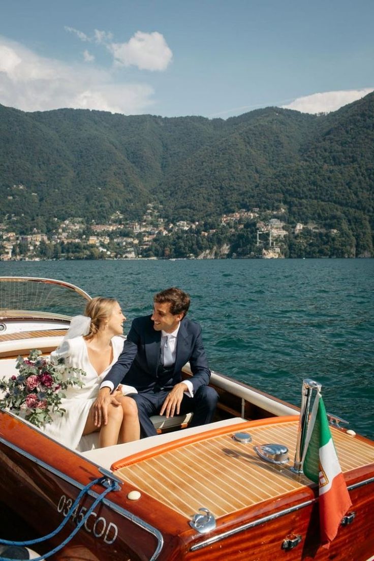 a bride and groom are sitting on the back of a boat in lake comoni