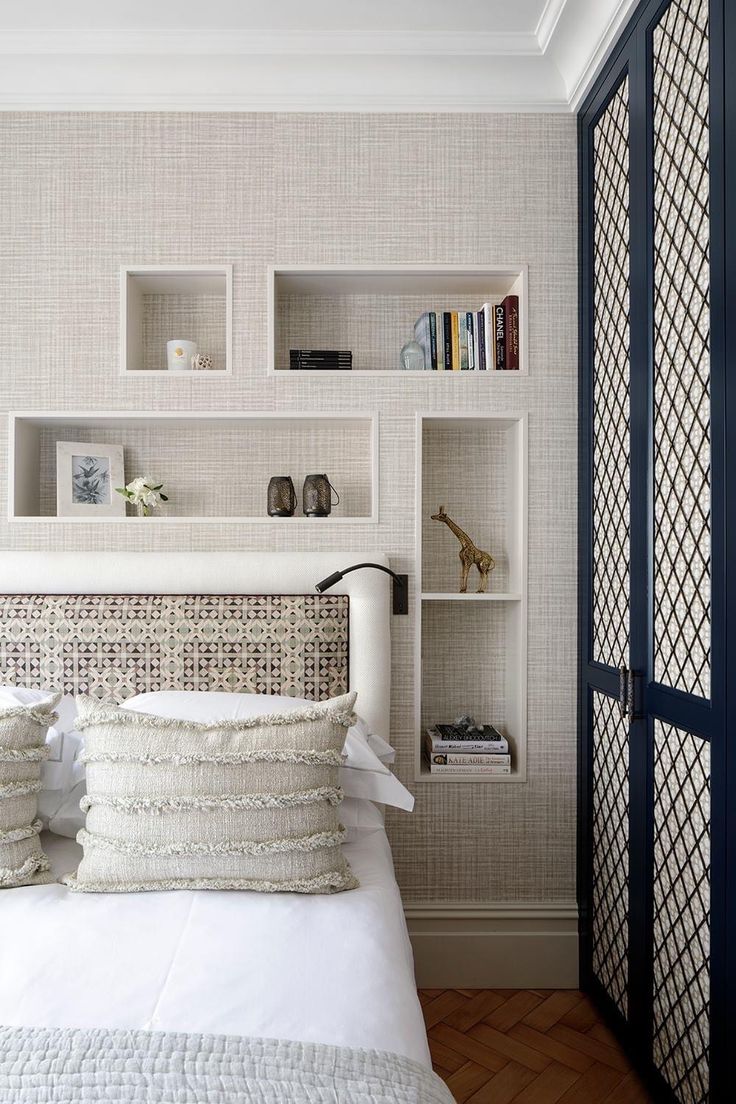 a bed with pillows and some books on the shelves