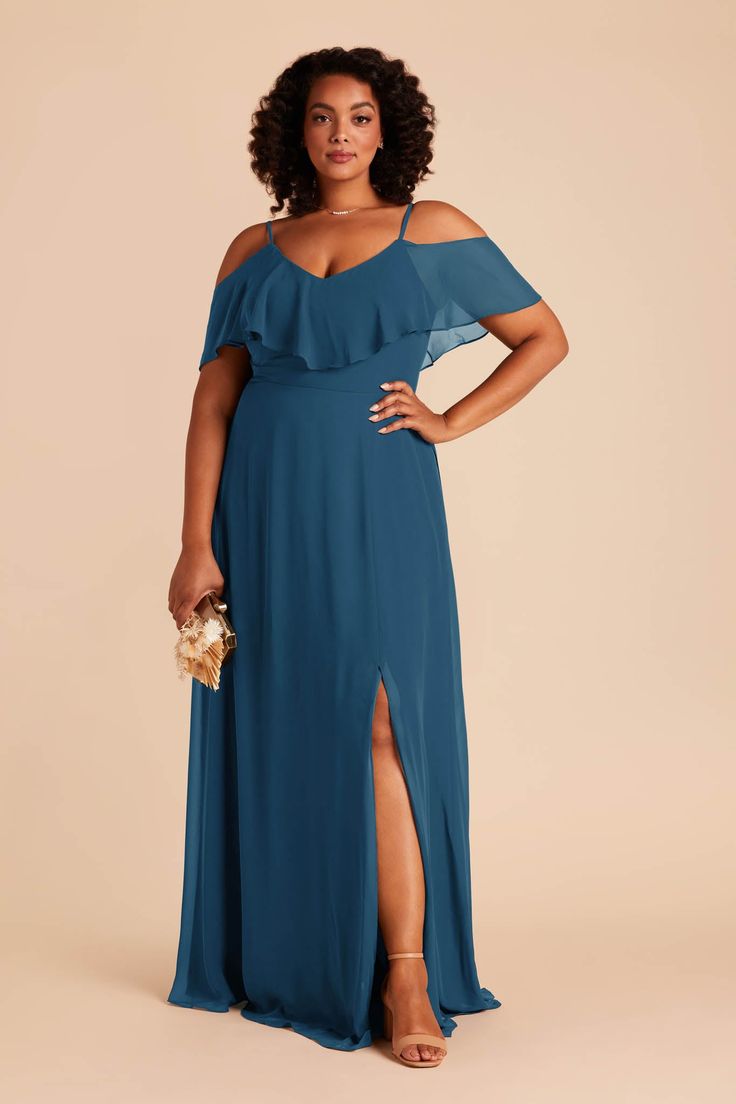 a woman in a blue dress with one leg slited up and her hand on her hip