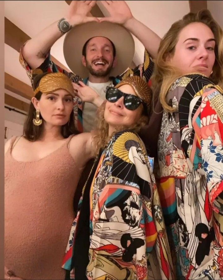 three women and one man are posing for the camera with hats on their heads in front of them