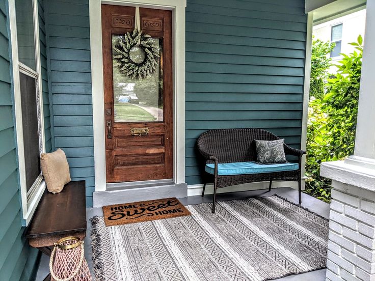 a front porch with a chair, rug and doormat on the side of it