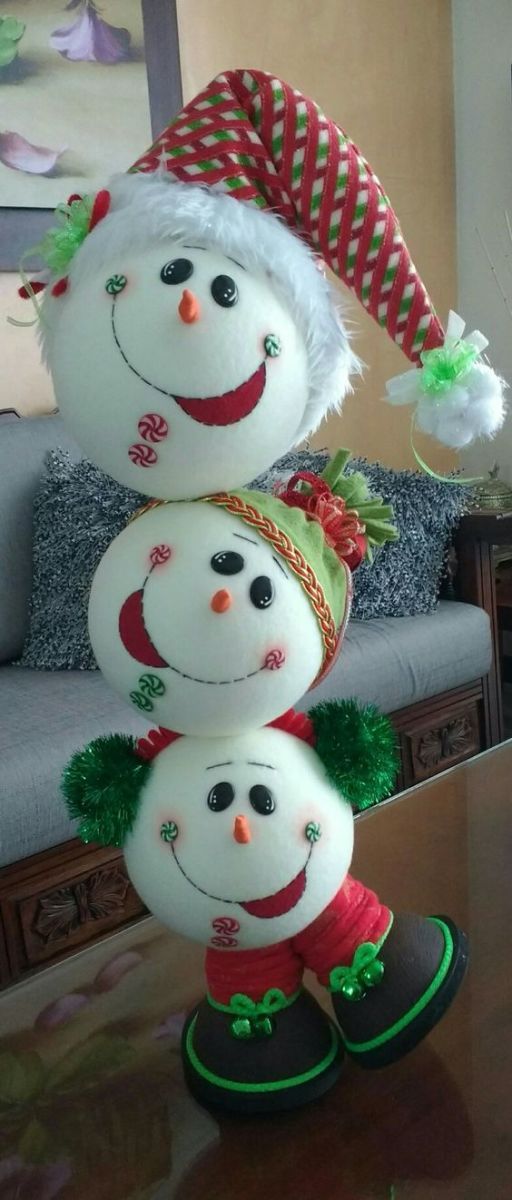 three snowmen with hats and scarves on their heads are sitting in front of a couch