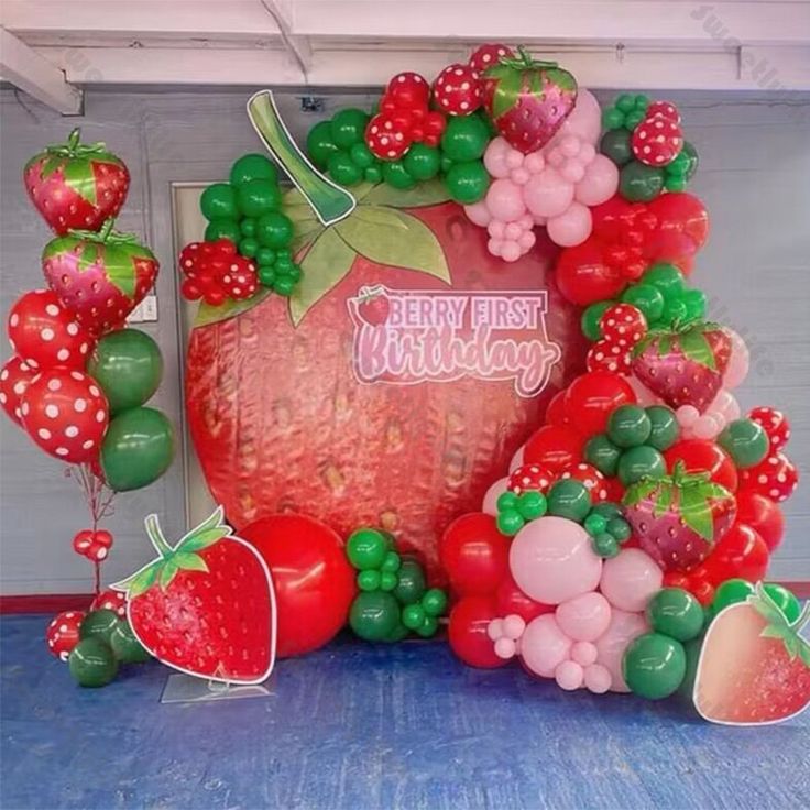 a large strawberry balloon display with balloons on the floor and decorations in front of it