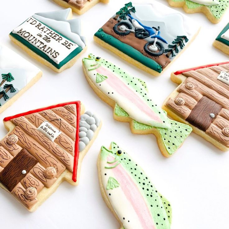 decorated cookies are arranged in the shape of boats, fish, and canoes on a white surface