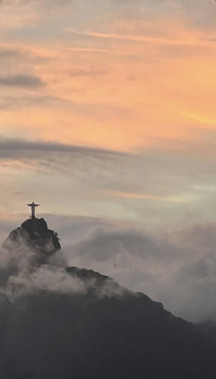 a cross on top of a mountain surrounded by clouds