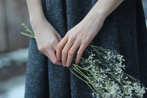 a close up of a person holding flowers in their hands and wearing a black dress