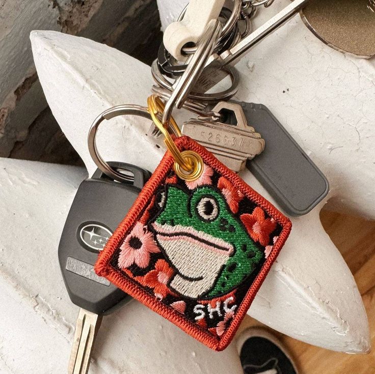 a keychain with a frog on it and some keys hanging from it's sides