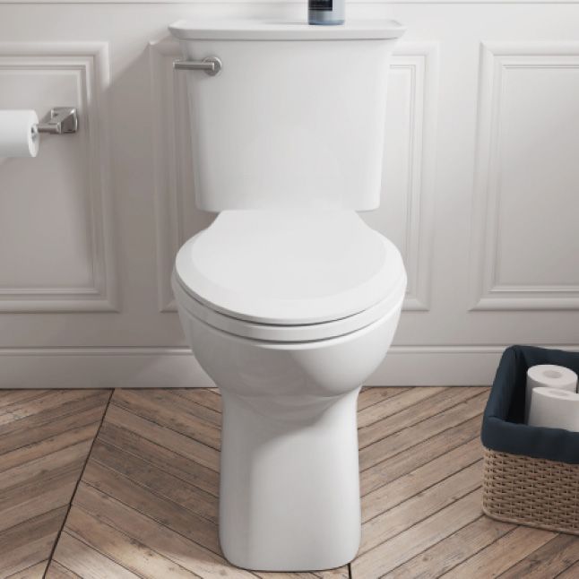 a white toilet sitting on top of a wooden floor next to a roll of toilet paper