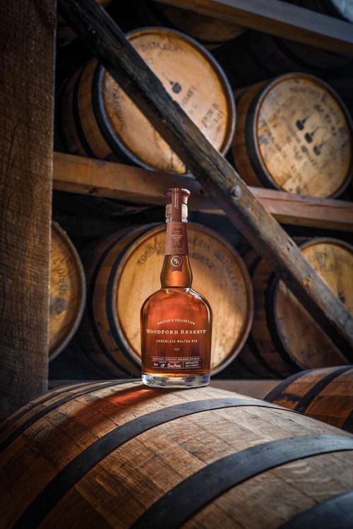 a bottle of whiskey sitting on top of wooden barrels