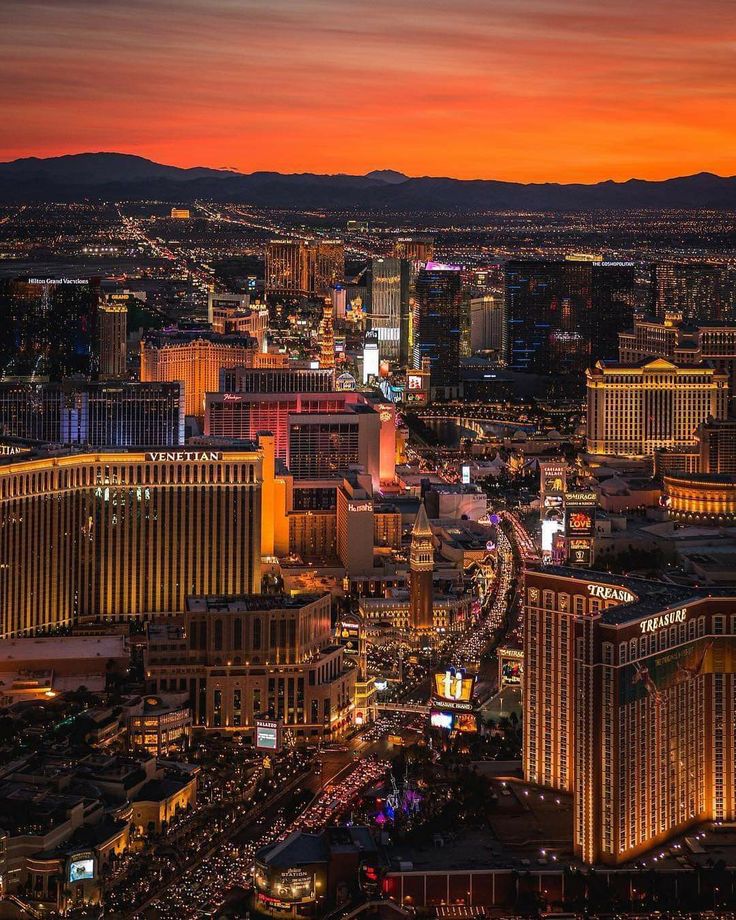 the las vegas strip is lit up at night, with mountains and buildings in the background