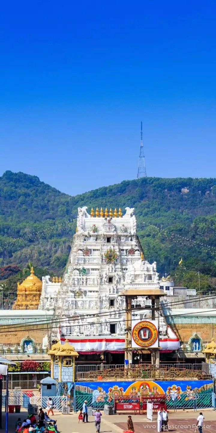 people are walking around in front of an elaborately decorated building with mountains in the background