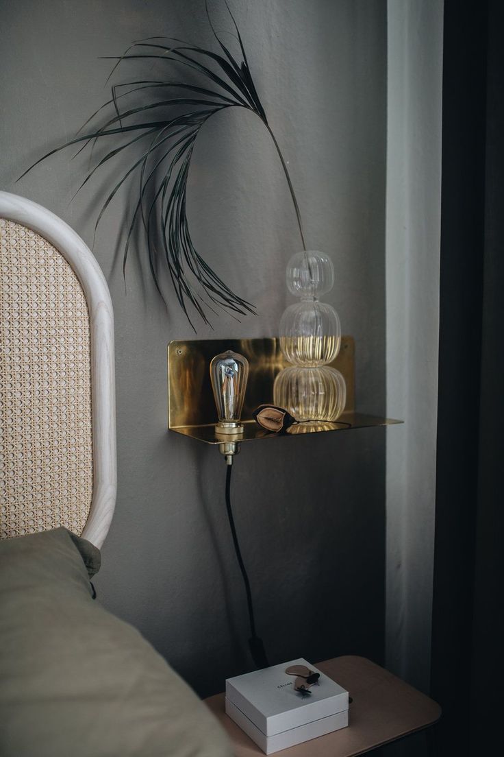 a bedroom with a bed, nightstand and plant on the wall next to the headboard